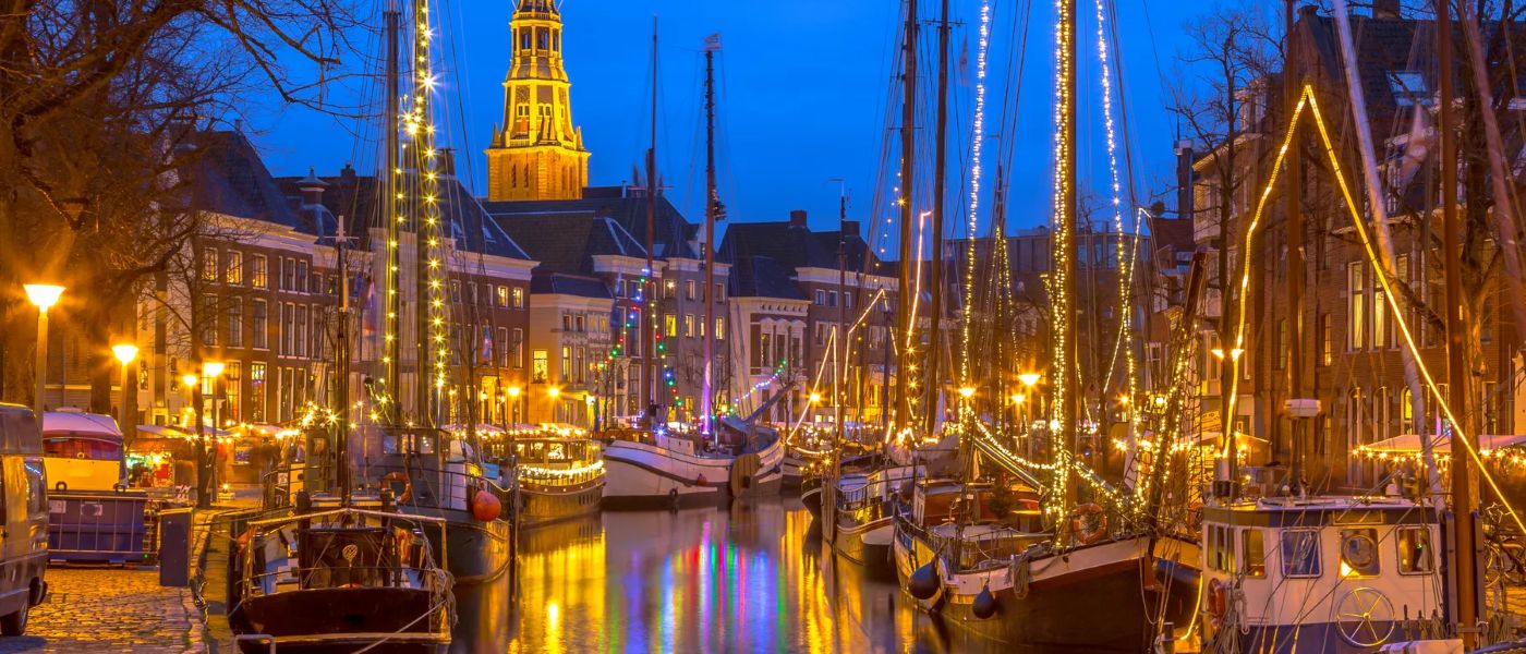 De Groningse binnenstad bij avond, aan het water met verlichte schepen